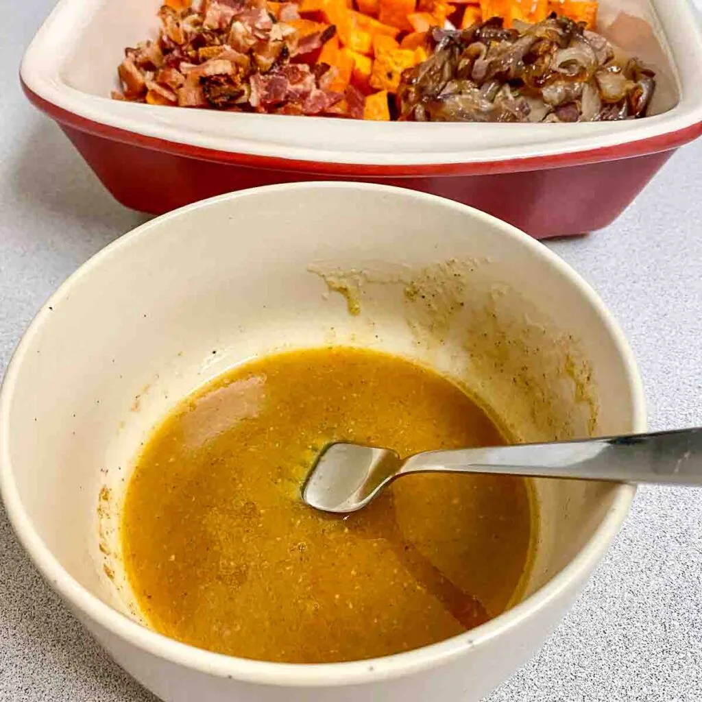 Assembling the sweet potato salad with the dressing.
