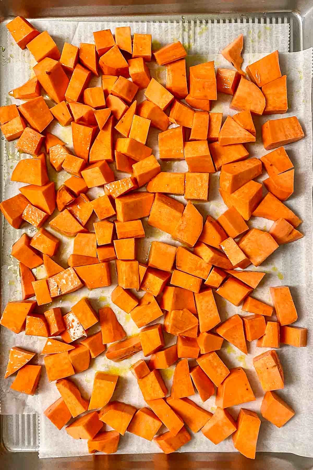 Raw Sweet Potatoes cubed on a baking tray.