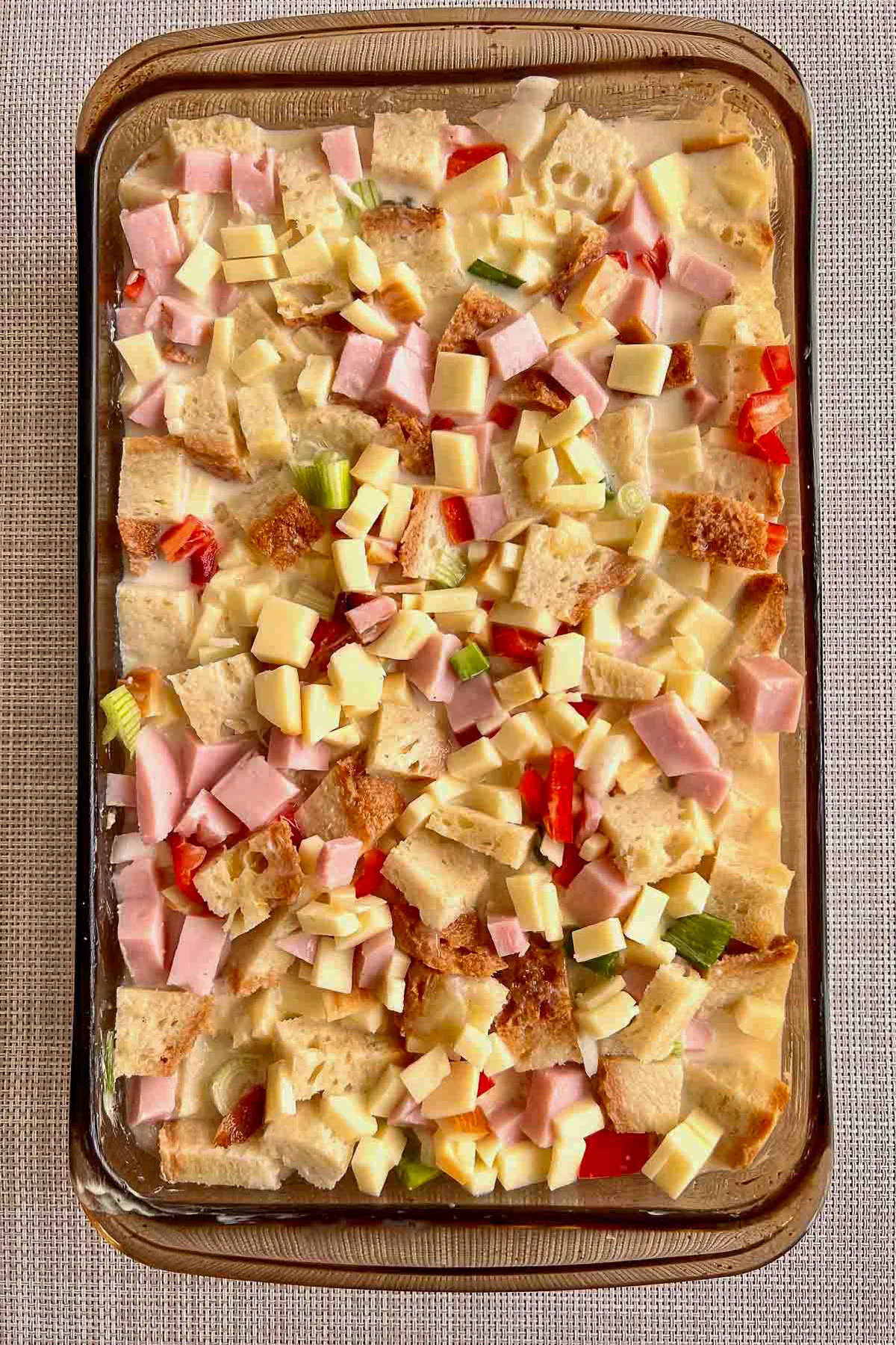Unbaked Ham And Cheese Strata in a glass baking dish.
