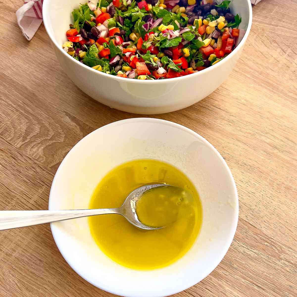 Olive oil and lemon dressing in a white bowl with spoon.