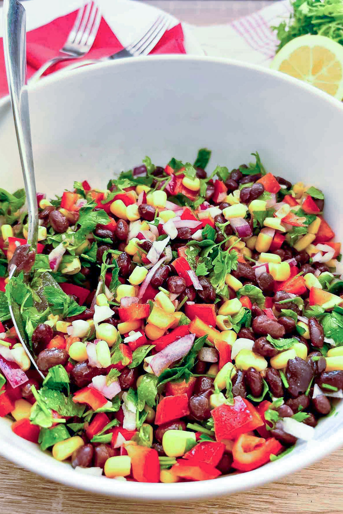 Black Bean Salad With Corn in a white bowl with spoon.