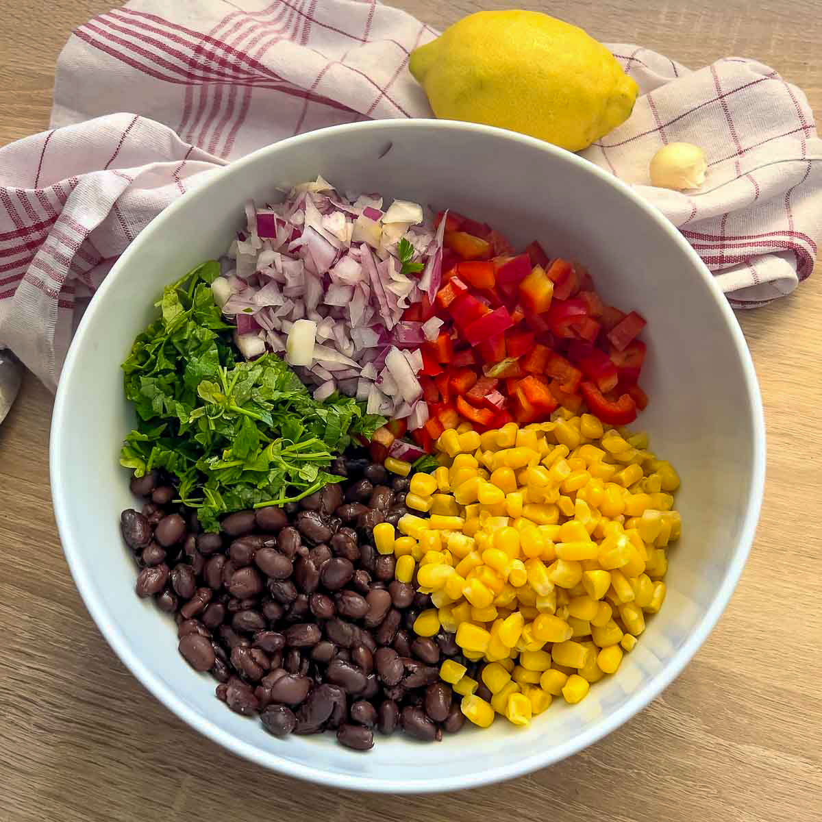 White bowl with chopped ingredients for the black bean salad.