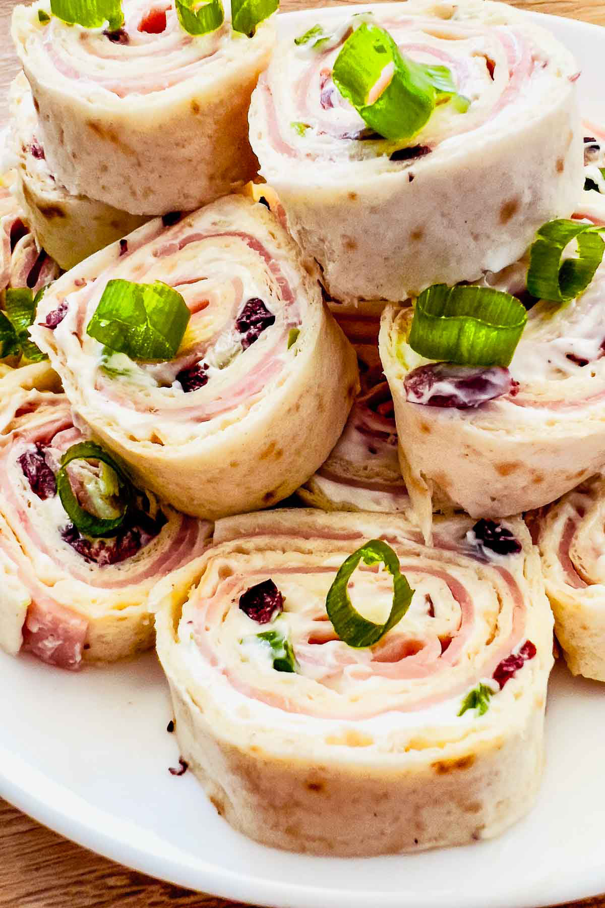 Tortilla roll ups stacked on a white platter.