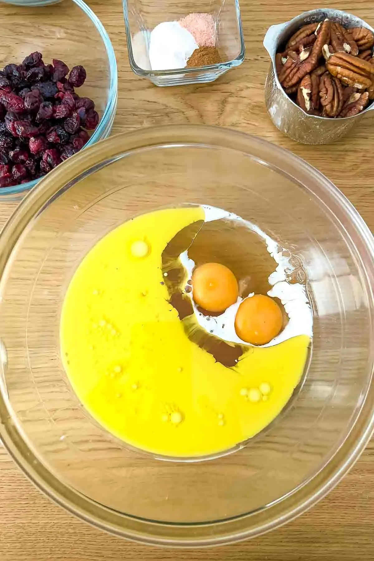 Honey eggs milk and oil in a glass bowl.