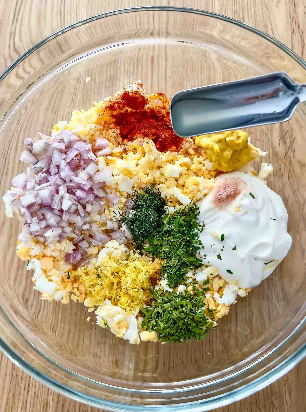 Adding lemon juice to the ingredients for egg salad with cream cheese.