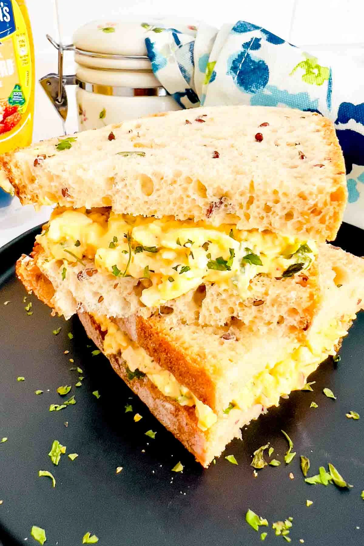 Egg Salad With Cream Cheese sandwich on a black plate.