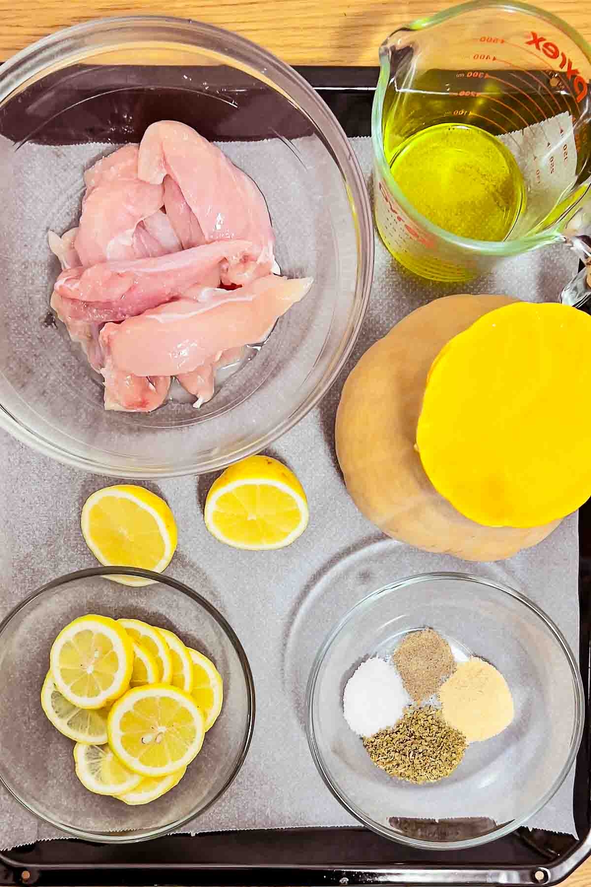 Ingredients for chicken with squash on a tray.