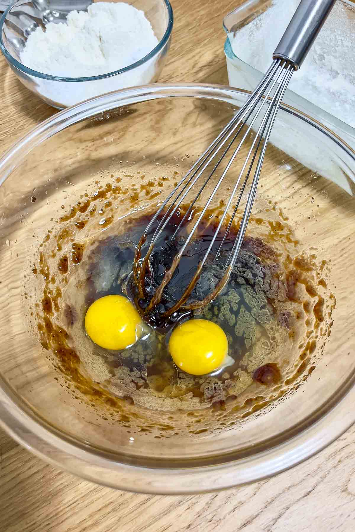 Eggs oil and brown sugar in a bowl.