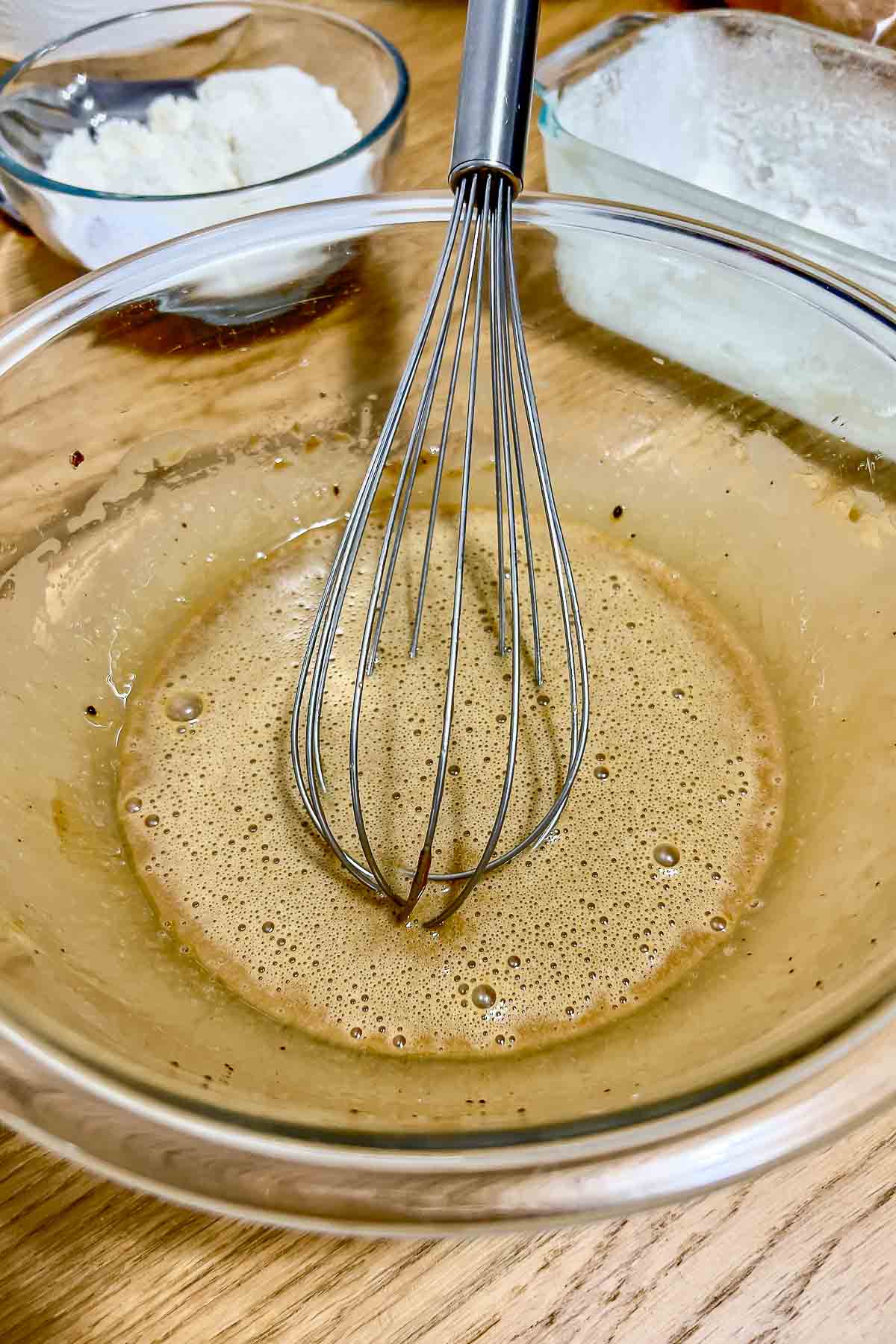 Eggs oil and brown sugar mixed in a bowl.