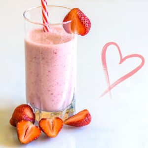 Berry Protein Shake in a tall glass decorated with fresh strawberries.