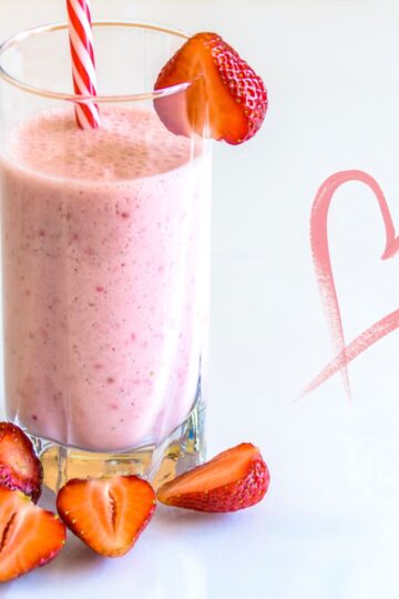 Berry Protein Shake in a tall glass decorated with fresh strawberries.