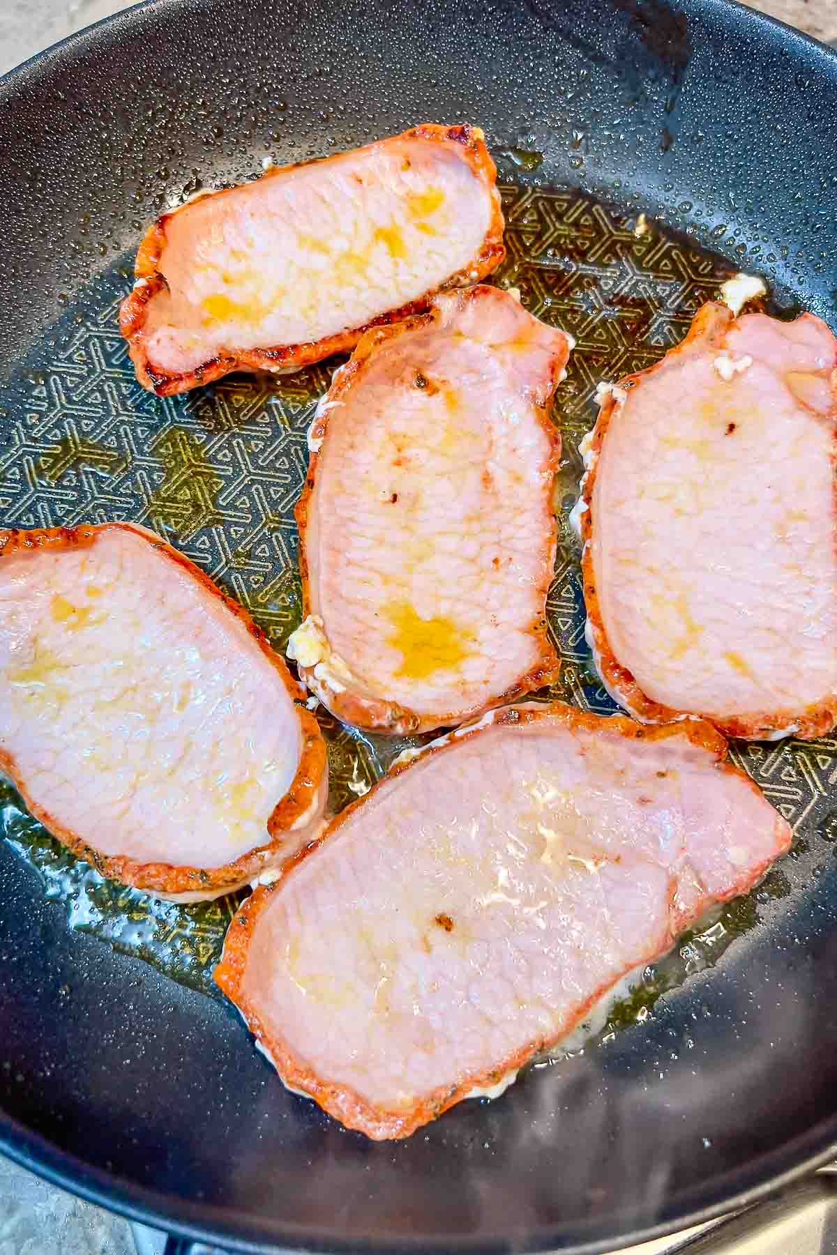 Pork Loin slices in adobo cooking in olive oil.