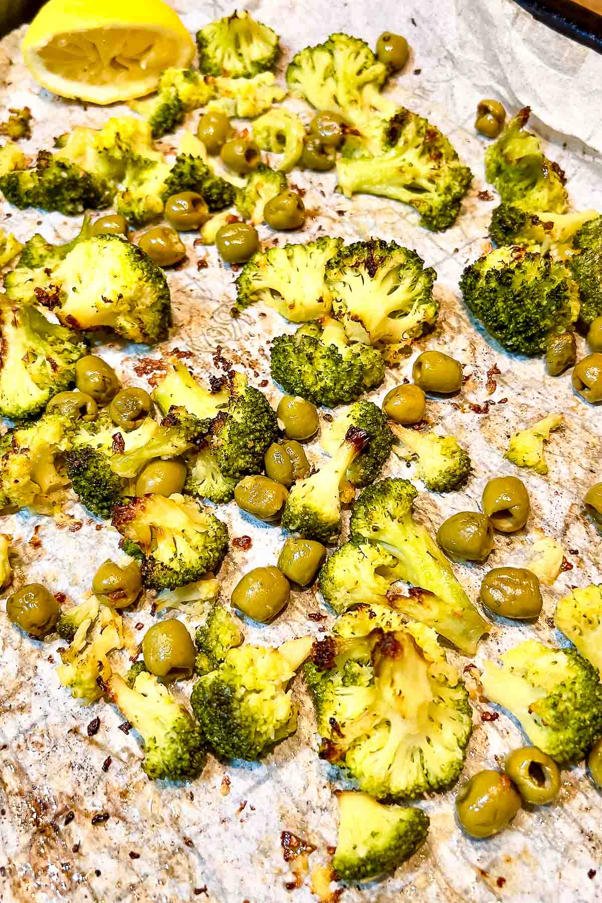 Roasted broccoli and olives on the baking tray.