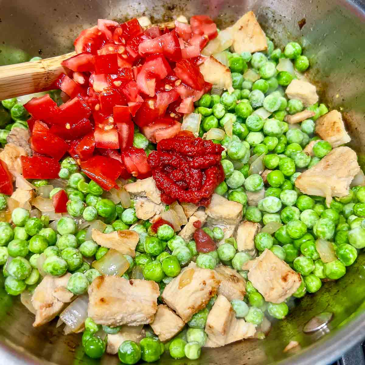 Adding diced tomatoes and tomato paste to the peas.