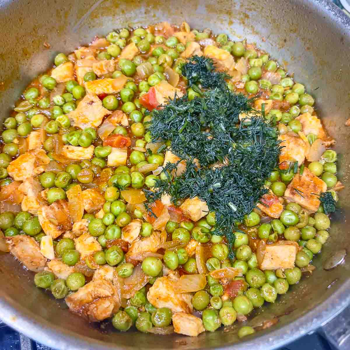 Adding dill to the peas and meat stew.