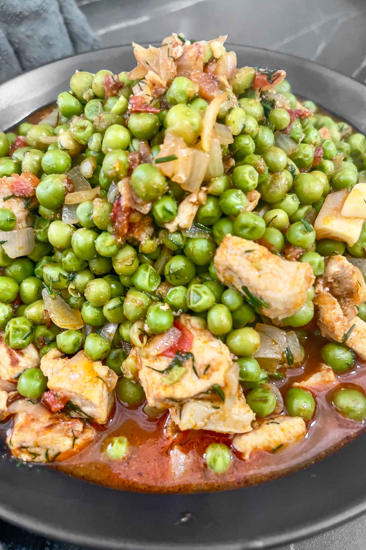 Pork and peas stew in a black bowl.