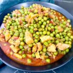 Pork and peas stew served in a black bowl.