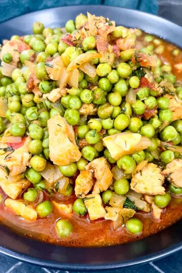 Pork and peas stew served in a black bowl.
