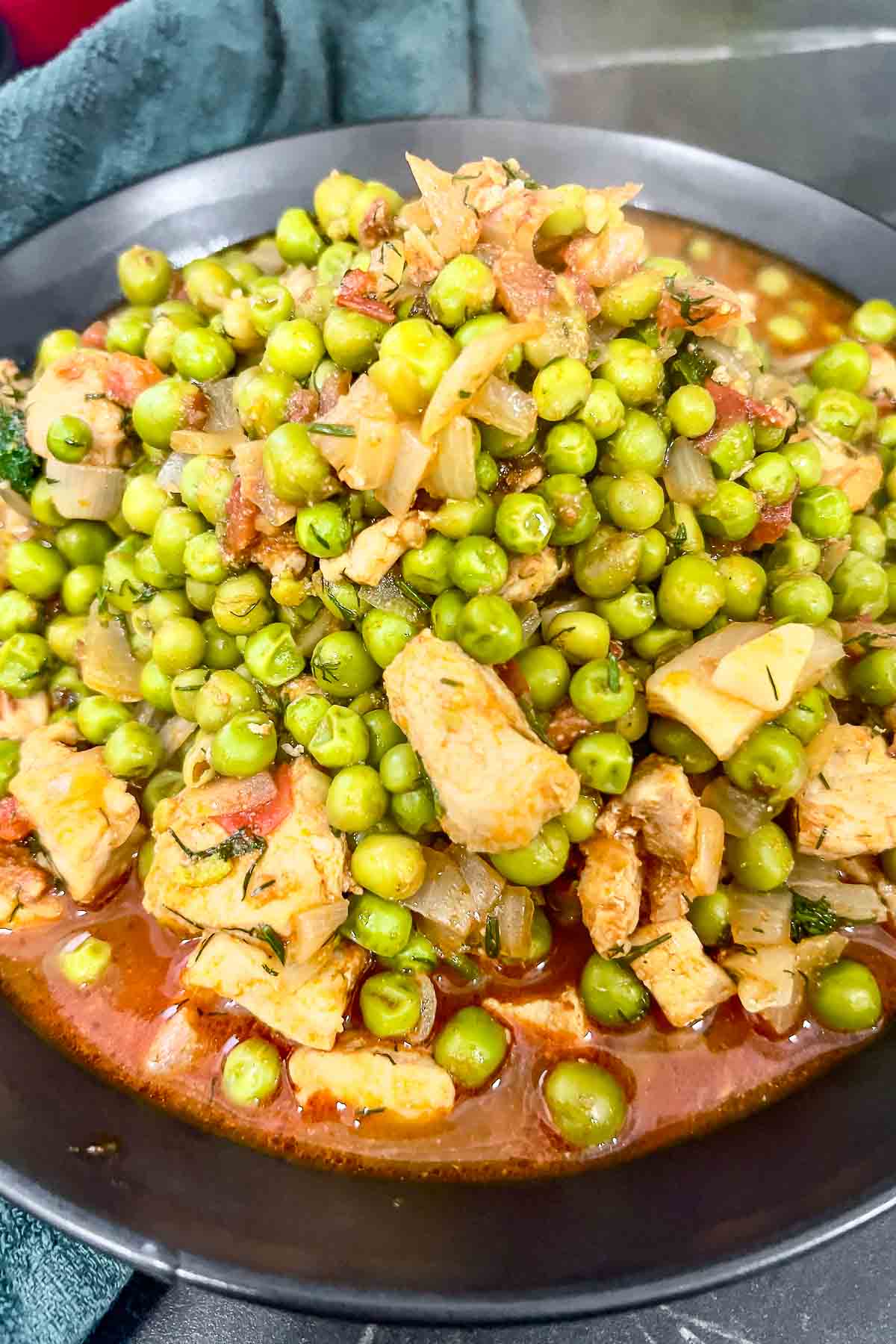 Pork and peas stew in a black bowl.